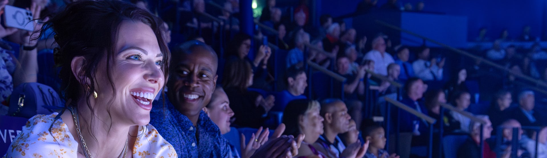 Happy couple in audience enjoying show on Icon of the Seas, excitement, fun, blue colors,