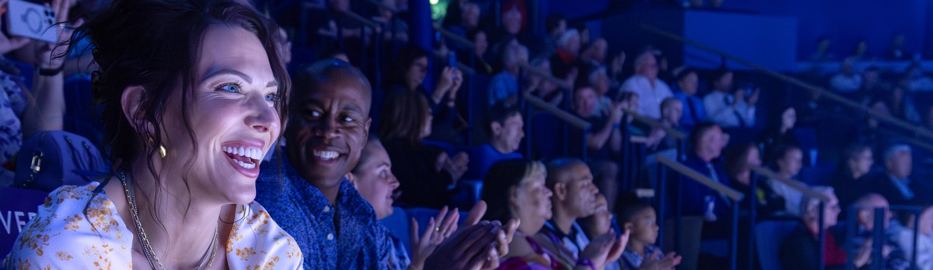 Happy couple in audience enjoying show on Icon of the Seas, excitement, fun, blue colors,