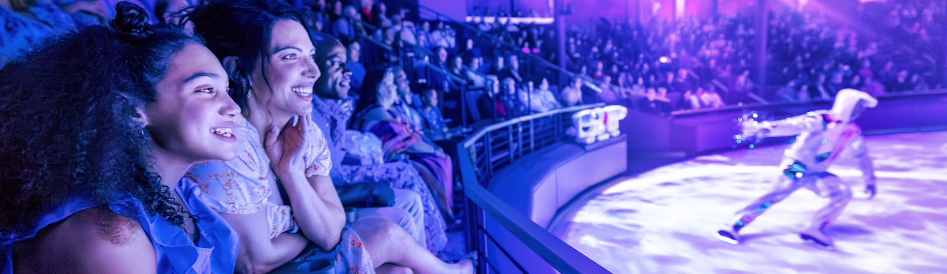 IC, Icon of the Seas, Mom and daughter watching ice show at Absolute Zero, audience, fun, entertainment, performer, show, blue and purple colors,