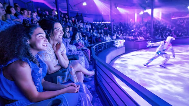 IC, Icon of the Seas, Mom and daughter watching ice show at Absolute Zero, audience, fun, entertainment, performer, show, blue and purple colors,