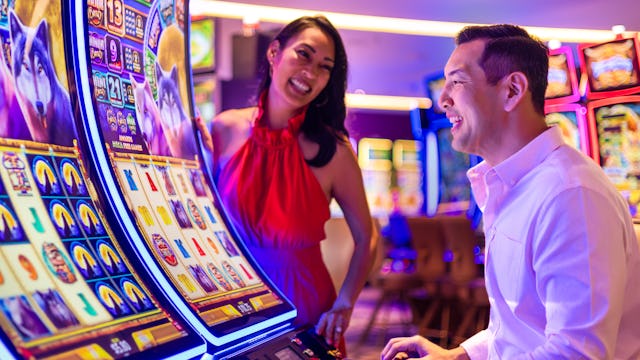 IC, Icon of the Seas, casino, couple at Casino Royale slot machine, fun, games, nightlife, excitement, anticipation,