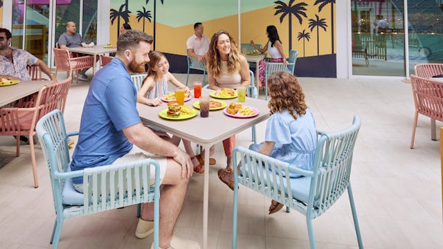 Family eating outside at Surfside Eatery onboard Icon of the Seas. Signage, family at table, casual dining, lunch.