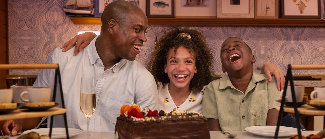 IC, Icon of the Seas, Dad and two kids celebrating together at Celebration Table in the AquaDome, family fun, laughter, VIP experience, decorated chocolate cake.