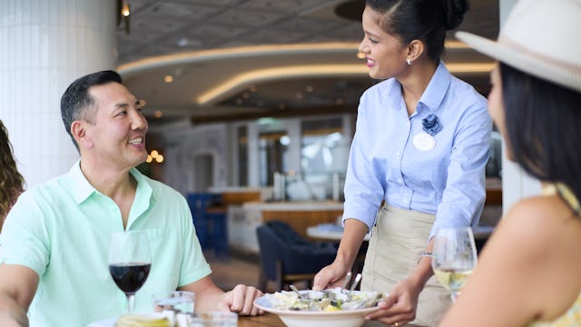 IC, Icon of the Seas, couple seated at Hooked Seafood, female waiter serving dish, restaurant, dining,