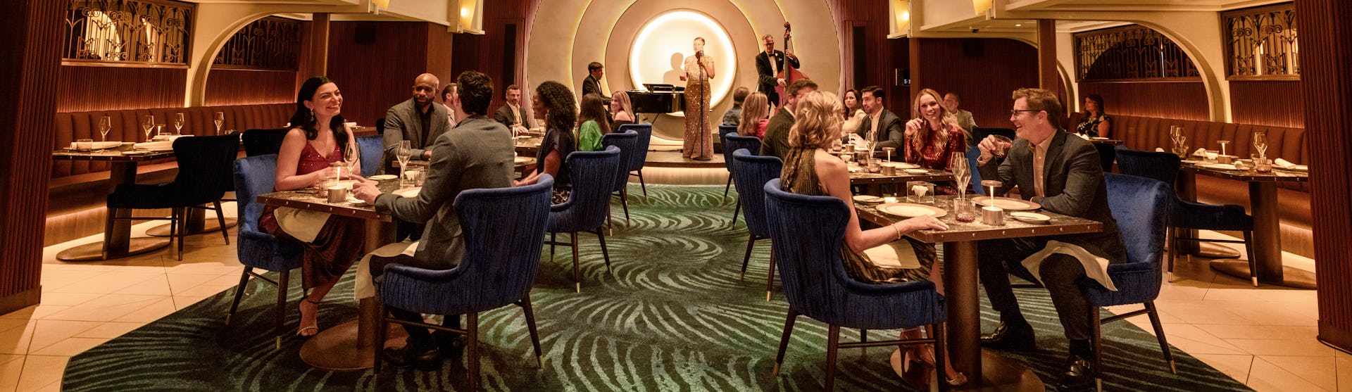 IC, dining room at Empire Supper Club onboard Icon of the Seas, wide shot, deco architecture, 1930s old New York theme, glamour, chandelier, jazz musicians on stage in the background, nightlife,