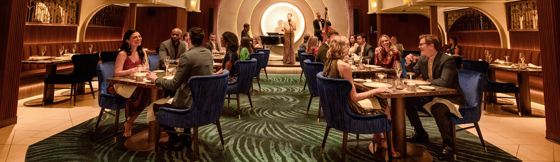 IC, dining room at Empire Supper Club onboard Icon of the Seas, wide shot, deco architecture, 1930s old New York theme, glamour, chandelier, jazz musicians on stage in the background, nightlife,