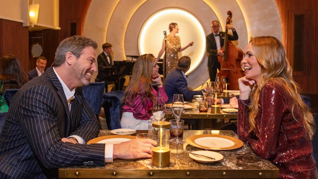 IC, Couple dining at Empire Supper Club onboard Icon of the Seas, musical group on stage in the background, nightlife, fun, evening, 1930s old New York theme, glamour,