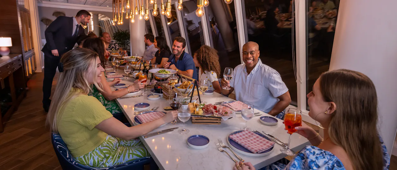 IC, Icon of the Seas, Group of family and friends at Celebration Table in AquaDome, VIP experience, long shot of table with guests and server in attendance, fun, enjoyment