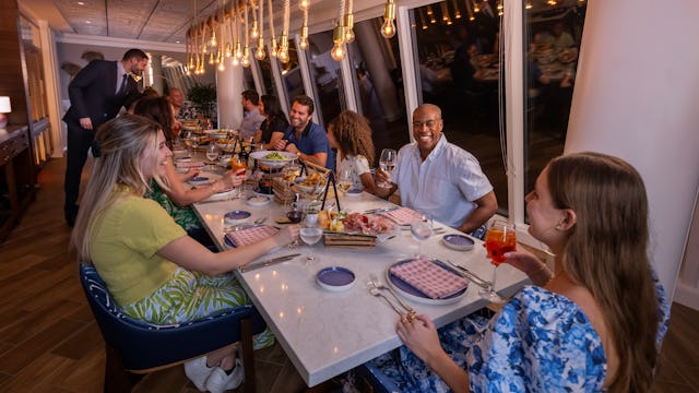 IC, Icon of the Seas, Group of family and friends at Celebration Table in AquaDome, VIP experience, long shot of table with guests and server in attendance, fun, enjoyment