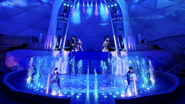 IC, Icon of the Seas, wide shot of performers, on stage in AquaTheater show. Aqua Action, fountains of water bubbling up, excitement, exciting, blue colors, stage lights,