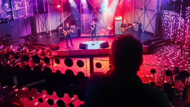 IC, Icon of the Seas, two people in audience looking down at live band playing at the Music Hall, performance, red colors,