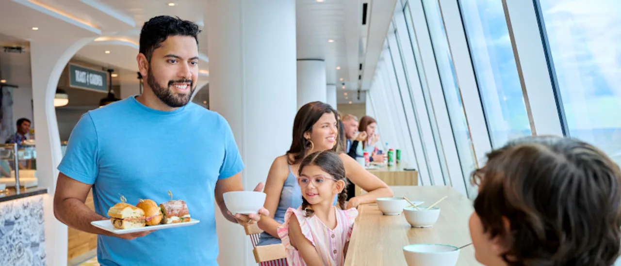 A father has brought some food for his children who are excited on board of the Icon of the Seas