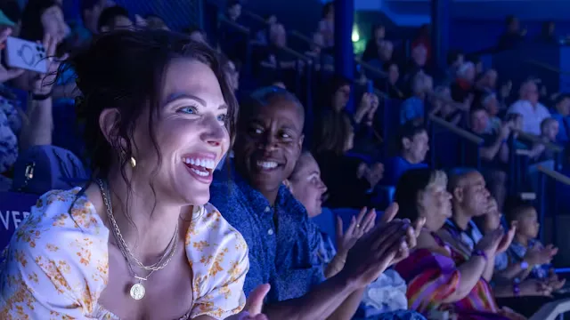 Vrolijke gasten genieten van een show in een theater op een cruiseschip en applaudisseren vanaf hun zitplaatsen.