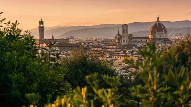 Uitzicht over Florence bij zonsondergang met de iconische koepel, omringd door groen en heuvels